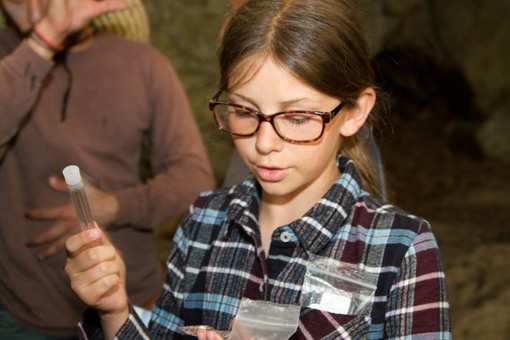 Photograph of a 5th grade girls, wearing glasses and holding a test tube.