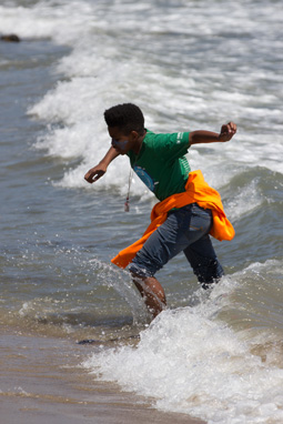 Photograph of a 5th grade boy playing along the Pacific shore wearing a CalWater H2O Challenge shirt.